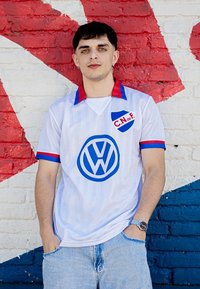 Witte trui met verticale strepen, rode en blauwe accenten, met een groot blauw Volkswagen-logo en schildembleem met de tekst "C.N. de F."