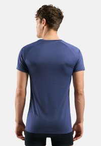T-shirt de sport bleu marine avec des manches courtes raglan, fabriqué à partir d'un matériau lisse et léger. Présente un design ajusté et des coutures minimales.
