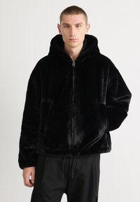 Black faux fur jacket with a hood, zip closure, and adjustable drawstring. Features a relaxed fit and soft texture.