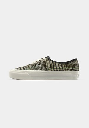 Baskets Vans à lacets avec une tige tissée texturée en vert et noir, semelle en caoutchouc blanc et détail de logo sur le côté.