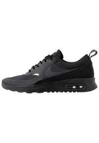 Chaussure de course Nike noire avec coussin d'air visible dans la semelle, tige en maille et languette au talon, montrée de côté sur fond blanc.