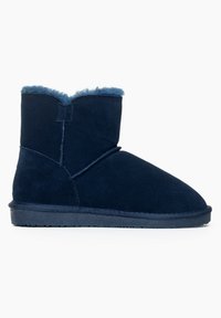 Botines de ante azul marino con forro mullido, puntera redondeada y suela de goma plana. Presenta un detalle de costura a lo largo del lateral.
