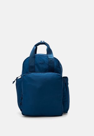 Sac à dos Levi's bleu foncé avec deux poignées supérieures, poche avant zippée et compartiments latéraux sur un fond uni clair.