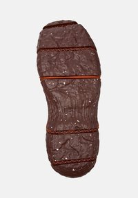 Brun, texturerad sula på en sko, med tydliga spår och en orange accent över bredden, där varumärket är synligt.