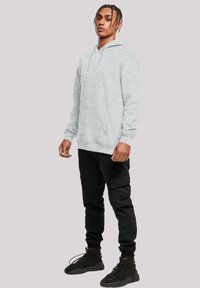 Gray pullover hoodie with a drawstring hood and front pocket, paired with black cargo pants, featuring multiple pockets and fitted cuffs.