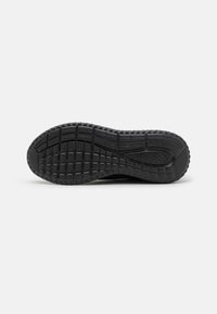 Suola di scarpa atletica nera con una superficie in gomma testurizzata, caratterizzata da un motivo esagonale e scanalature per la trazione.