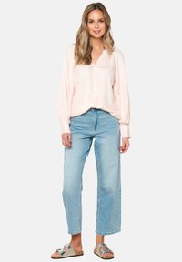 Light pink button-up shirt with a relaxed fit and long sleeves, paired with light blue high-waisted jeans and gray sandals with a cork sole.
