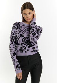 Fioletowy dziergany sweter z czarnym wzorem paisley, okrągłym dekoltem i długimi rękawami, zestawiony z dopasowanymi czarnymi spodniami.