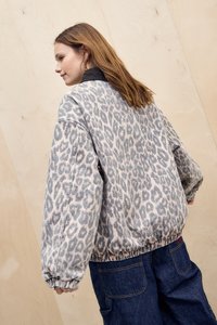 Jaqueta de ganga com padrão de leopardo, com bainha elástica, corte oversized e colarinho escuro, combinada com jeans largos azuis.