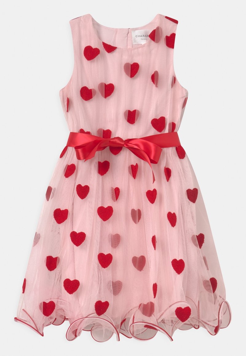 Różowa sukienka z czerwonymi filcowymi wzorami w kształcie serc, bez rękawów, z czerwonym satynowym paskiem w talii. Posiada falbaniasty dół.
