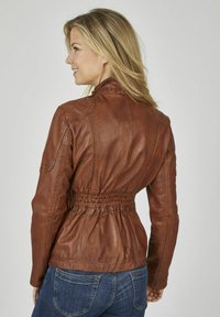 Braune Lederjacke mit taillierter Silhouette, hohem Kragen und glatter Textur. Verfügt über detaillierte Nähte und lange Ärmel.