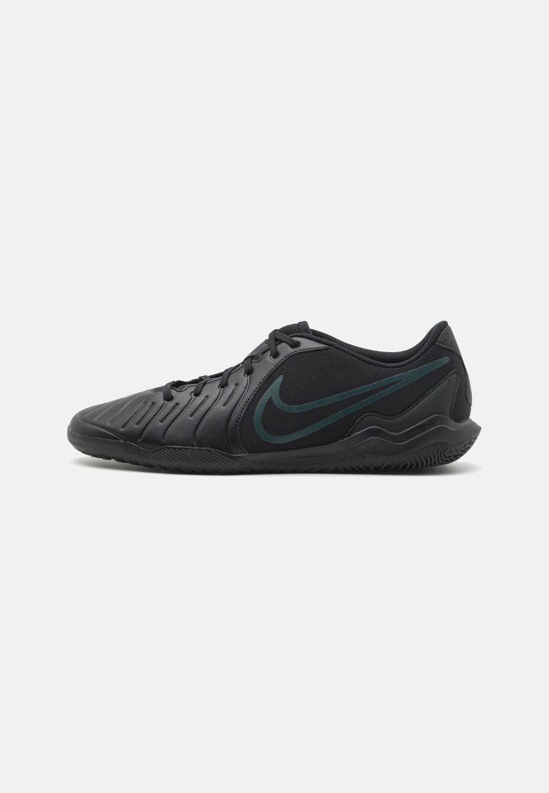 Ténis atléticos pretos com parte superior de material sintético texturizado, sistema de atacadores largo e logo da Nike em verde escuro contrastante na lateral. Sola de borracha.