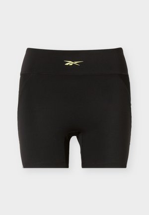 Fekete, magas derekú sportnadrág kis sárga logóval a derékszíjon középen, egyszerű világos háttér előtt bemutatva.