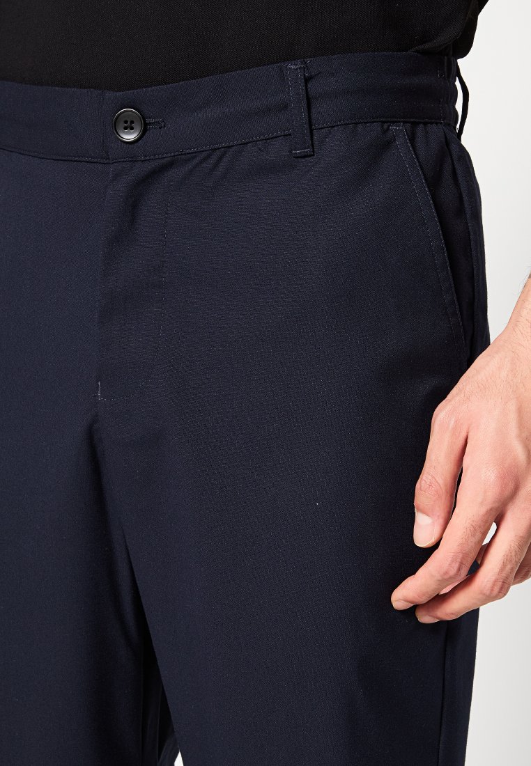 Marineblaue, leichte Hosen mit einer glatten Textur, einem Knopfverschluss und Fronttaschen. Zeigen eine taillierte Passform mit einem elastischen Taillenbund.
