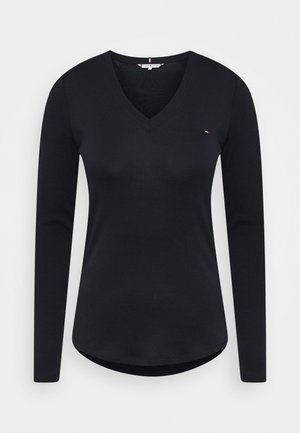 Zwarte lange mouwen V-hals shirt met een klein rood, wit en blauw logo op de linkerborst en een gebogen zoom.