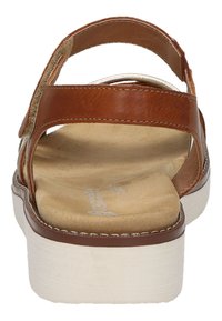 Braune Ledersandale mit mehreren Riemen, einem gepolsterten beigefarbenen Fußbett und einer dicken weißen Sohle. Mit Kontrastnähten und glatter Textur.
