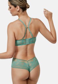 Teal kanten lingerie set met doorzichtige accenten, voorzien van bloemmotieven, verstelbare bandjes en goudkleurige hardware voor een veilige sluiting.