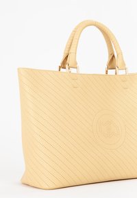 Gul perforeret læder tote taske med dobbelt håndtag og hardware i guldtone. Udstyret med et debosseret logo og struktureret form.