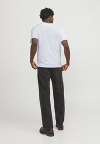 Light blue cotton t-shirt with short sleeves, round neck, and relaxed fit. Paired with black denim pants and brown boots.