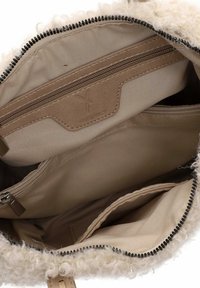 Šviesiai rudos spalvos audinio rankinės vidus su keliais užtrauktukais ir atviromis kišenėmis, išklotas šviesiai rudos tekstilės ir apipjaustytas garbanojančia balta dirbtine kailiuku.