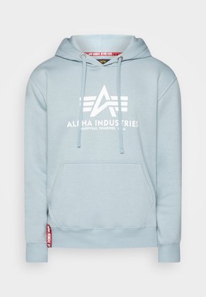 Hellblaues Hoodie mit einer Kängurutasche, Zugbändern und einem großen weißen "ALPHA INDUSTRIES" Logo. Hat gerippte Bündchen und ein Markenetikett.