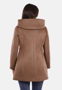 Cappotto aderente marrone con colletto largo e ripiegato, maniche lunghe e tessuto liscio e strutturato. Parte posteriore sagomata con dettagli di cucitura senza cuciture.