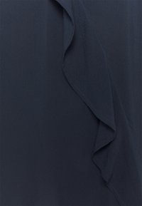 Tessuto blu navy con un dettaglio di volants che scorre lungo un bordo, texture liscia e un leggero lucido. La cucitura è ordinata e uniforme.