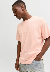 Heledad roosa lühikeste varrukatega T-särk, mis on valmistatud pehmest kangast, väikese tikitud logoga rindKERIS ja lõdva lõikega.