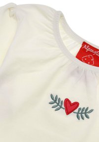 Cream shirt with gathered shoulders, featuring red embroidered heart and green leaves. Tag is red with white lettering.