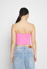 Różowy prążkowany top z krótkim rękawem z cienkimi, koralikowymi ramiączkami, w połączeniu z jasnoniebieskimi dżinsami z wysokim stanem. Prosty design z dopasowaną sylwetką.