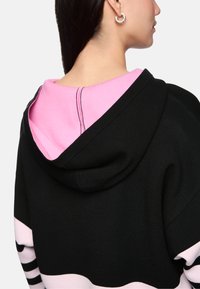 Hooded sweatshirt with a black body, pink interior, and light pink bottom. Features horizontal stripes and visible stitching details.