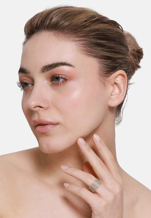 Silberring mit strukturierten Bändern, der auf einer Hand präsentiert wird und ein kompliziertes Design zeigt. Modell mit glatter Haut, minimalem Make-up und natürlichen Nägeln.