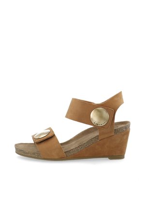 Brune læder wedge sandal med en tekstureret korksål, bred ankelrem og store metalliske knapdetaljer på justerbare stropper.