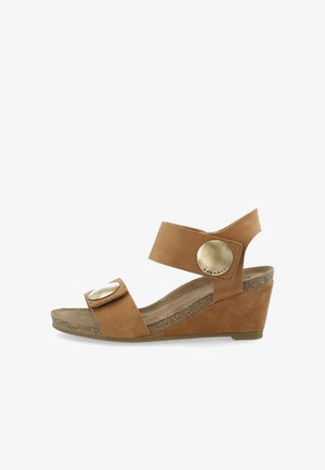 Brune læder wedge sandal med en tekstureret korksål, bred ankelrem og store metalliske knapdetaljer på justerbare stropper.
