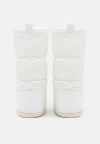 Bottes blanches matelassées au design bouffi, dotées d'une semelle en caoutchouc lisse et d'un talon plat avec une seule boucle pour faciliter l'enfilage.