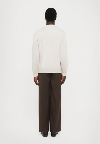 Light gray sweater with a round neckline and ribbed cuffs, paired with dark brown wide-leg trousers and black shoes, viewed from the back.