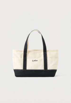 Cream canvas tote bag with black handles and bottom, featuring "LeGer" logo on front center pocket.