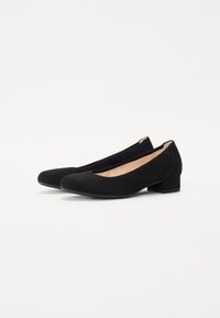 Bailarinas de ante negro con puntera redonda y un bajo tacón cuadrado. Textura suave, diseño minimalista y silueta simple y elegante.