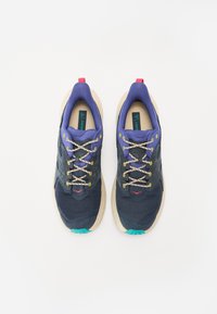 Scarpe da ginnastica blu e viola con tomaia in rete, suola beige e dettagli verde chiaro. Presentano lacci rotondi e un'etichetta sul tallone rossa.