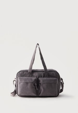 Sac à main rectangulaire en velours côtelé gris foncé avec deux poches zippées à l’avant, deux poignées et une bandoulière réglable sur fond blanc.