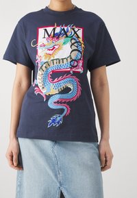 Granatowy bawełniany T-shirt z kolorową grafiką smoka i napisem „MAX”. Krótkie rękawy, luźny krój, zestawiony z jeansową spódnicą.