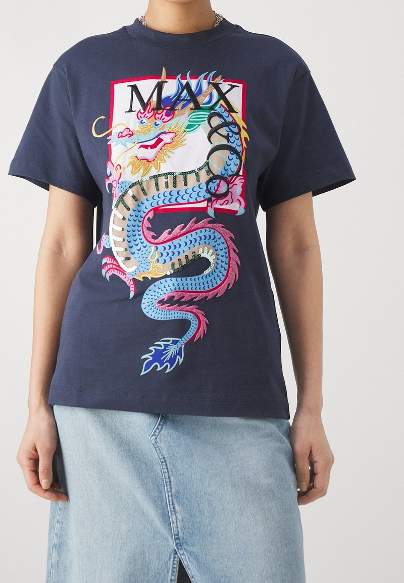 Granatowy bawełniany T-shirt z kolorową grafiką smoka i napisem „MAX”. Krótkie rękawy, luźny krój, zestawiony z jeansową spódnicą.