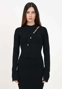 Top de punto negro con mangas largas y cuello alto. Presenta un corte diagonal con acentos de botones dorados a lo largo de un lado. Diseño ajustado.