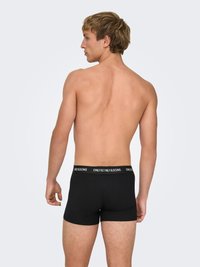 Zwarte boxershorts met een rekbare tailleband met het logo "ONLY & SONS." Model toont een neutrale pose van achteren.