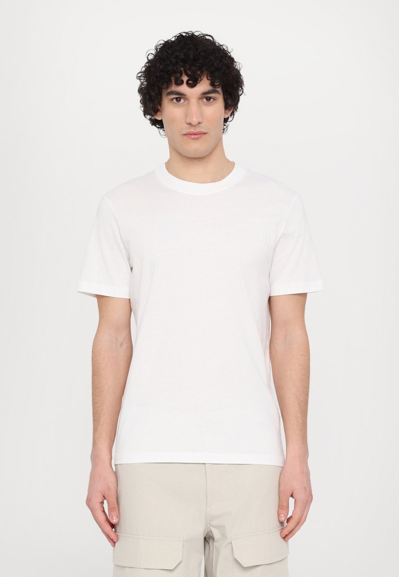 Tricou alb din bumbac, cu mâneci scurte, guler rotund și logo brodat subtil pe pieptul stâng. Textură netedă, croială casual.