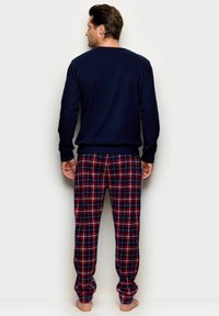 Tummansininen pitkähihainen paita yhdistettynä ruutupantoihin, joissa on punaisia ja vihreitä viivoja, valmistettu pehmeästä kankaasta; rento malli mukavuutta varten.