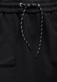 Schwarze Shorts mit einem elastischen Bund und verstellbarem Kordelzug. Ausstattung mit zwei seitlichen Taschen und glatter Stoffoberfläche.