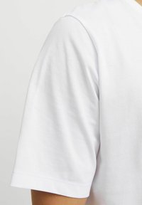 Witte T-shirt met korte mouwen van zacht katoen, met een ronde halslijn en schone stiksels langs de mouwen en de zoom.