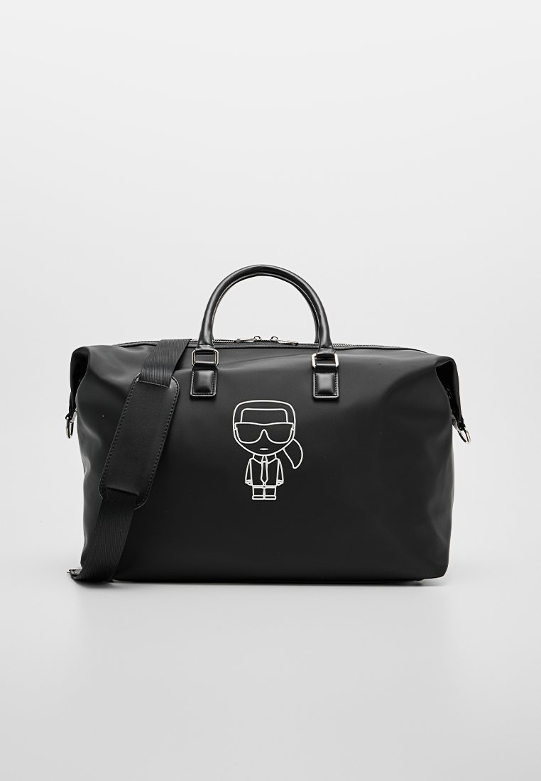 Bolsa tipo duffel negra hecha de material liso, con un gráfico de un personaje de dibujos animados en blanco y dos asas con una correa de hombro ajustable.