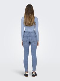 Light blue ribbed long-sleeve top paired with high-waisted, skinny denim jeans. Jeans feature two back pockets and a fitted silhouette.